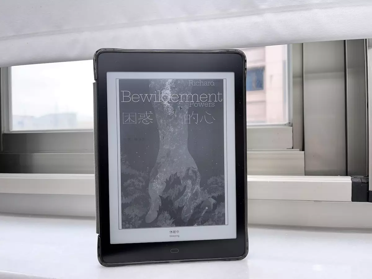 這是一張HyRead黑白電子書閱讀器立在窗台邊的大理石窗台上，電子書上的封面即是理察鮑爾斯的繁體中文翻譯著作困惑的心的封面