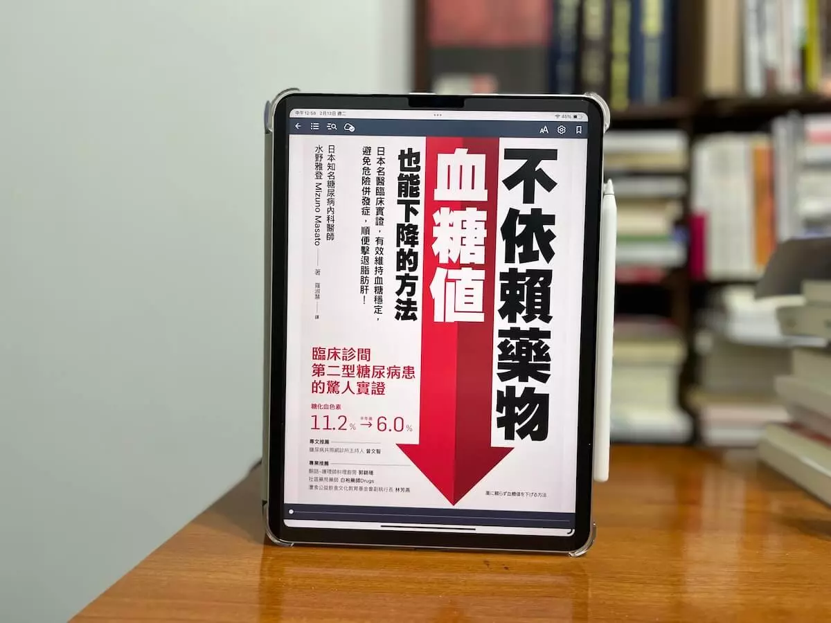 這日一張在書櫃前的原木書桌，書桌上立著一個iPad Pro，螢幕上是日本醫師所著《不依賴藥物，血糖值也能下降的方法》的繁體中文電子書封面
