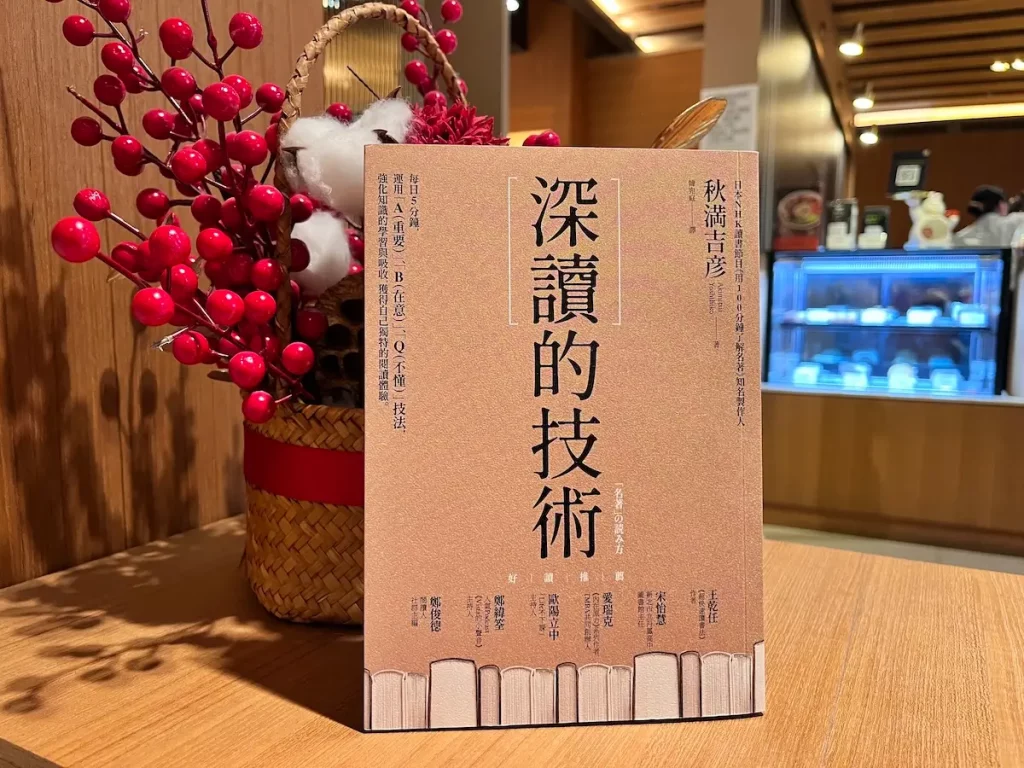 日本作家秋滿吉彥著作的深讀的技術紙本書立在咖啡館邊桌上，書後有喜氣的裝飾物